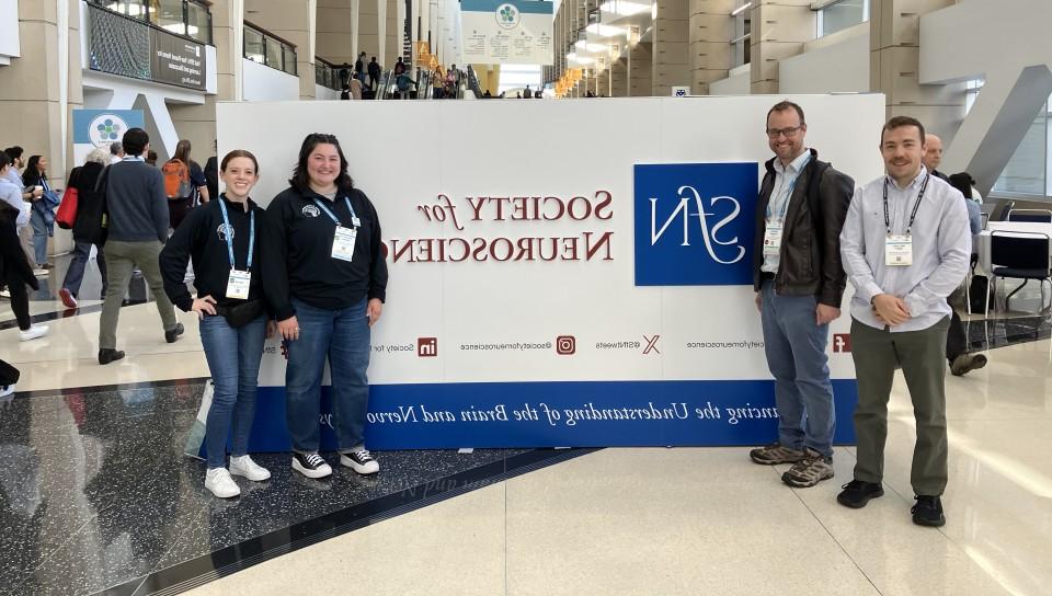 A group of UNE researchers pose in front the Society for Neuroscience sign