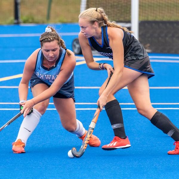 A U N E women's field hockey player during a game on the blue field