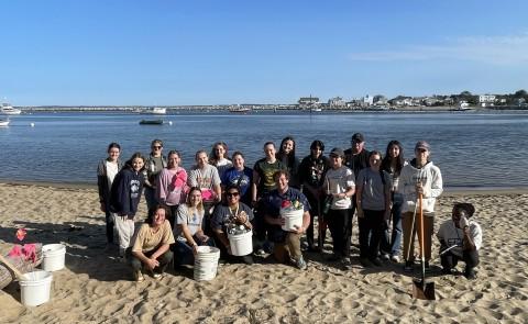 A group of students pose with buckets on Freddy Beach after cleaning up the sands